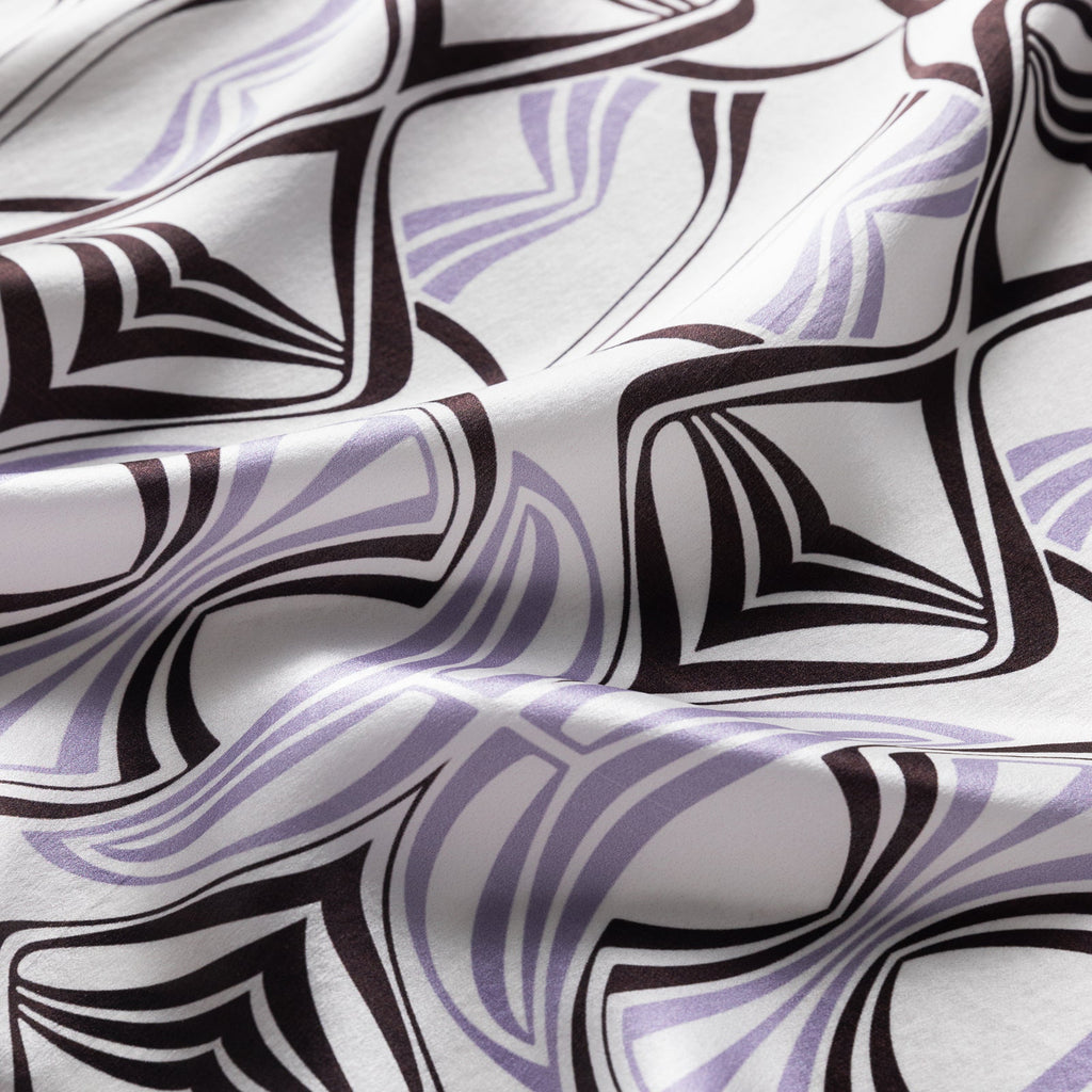 Closeup image of a silk scarf printed with a lavender and dark brown art nouveau pattern