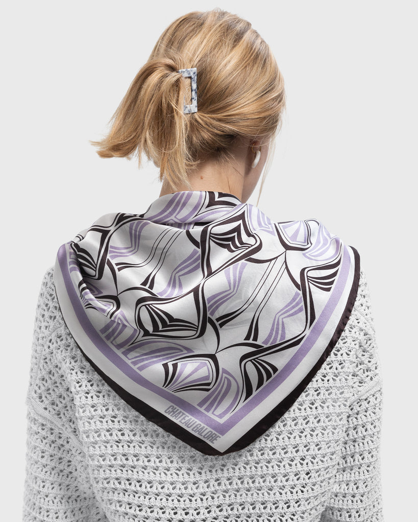 Backview of a blonde woman wearing a silk scarf with a art nouveau inspired pattern