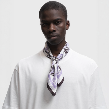 Model with buzzcut wearing a silk scarf with a lavender/dark brown art nouveau pattern