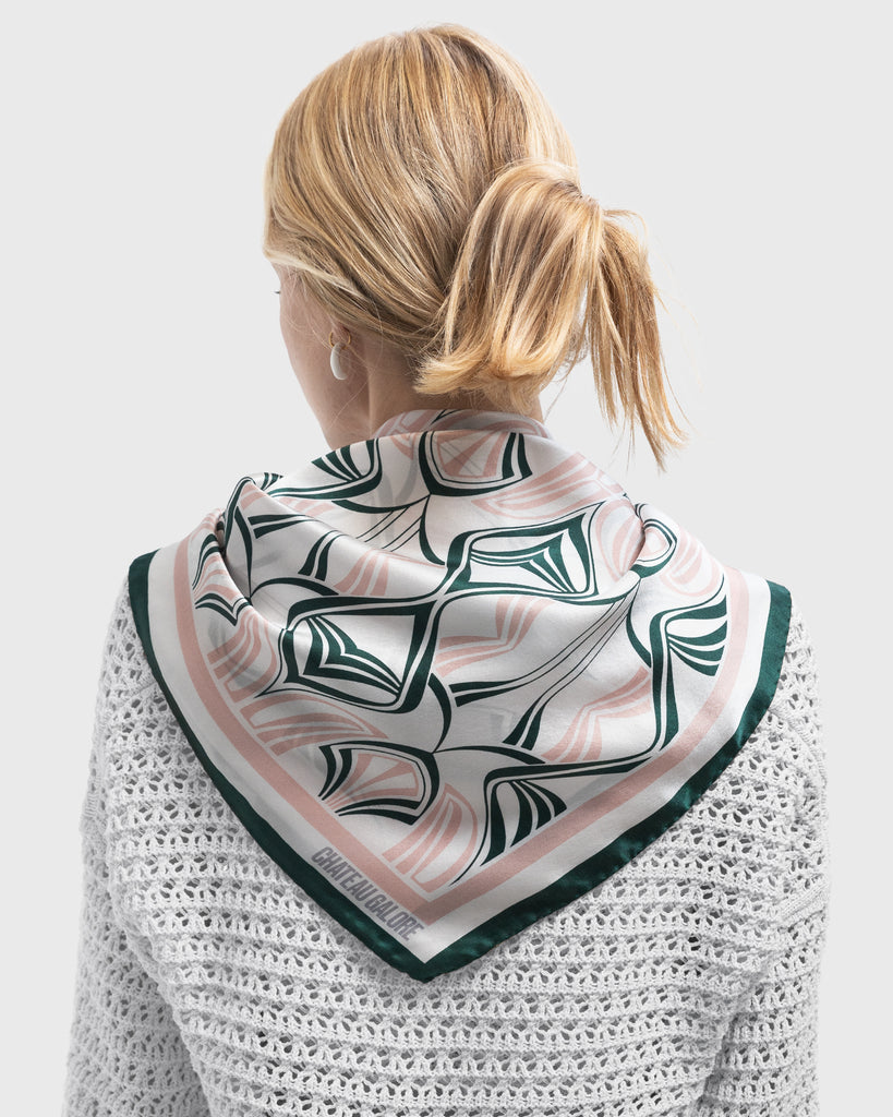 Backview of a blonde woman wearing a silk scarf with a art nouveau inspired pattern