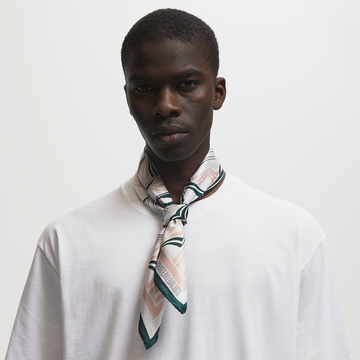 Model with buzzcut wearing a silk scarf with a dusky pink/forest green art nouveau pattern