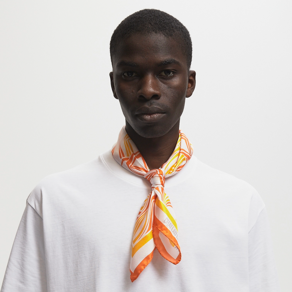 Model with buzzcut wearing a silk scarf with a orange/yellow art nouveau pattern